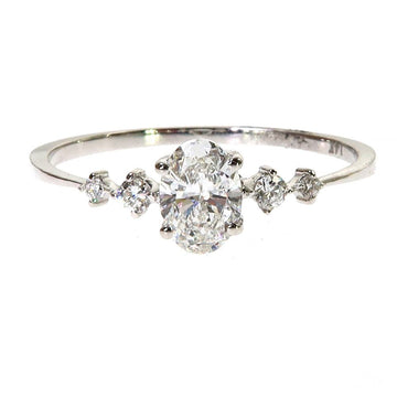 White gold oval diamond ring with six surrounding smaller diamonds on slender band.