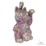 Cat figurine encrusted with multicolored sapphire crystals, raised paw design.