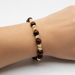 Adjustable men's bracelet with polished red tiger eye and textured gold beads on black cord.