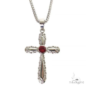 Silver cross pendant with intricate designs and round red rhodolite gemstone center on chain.