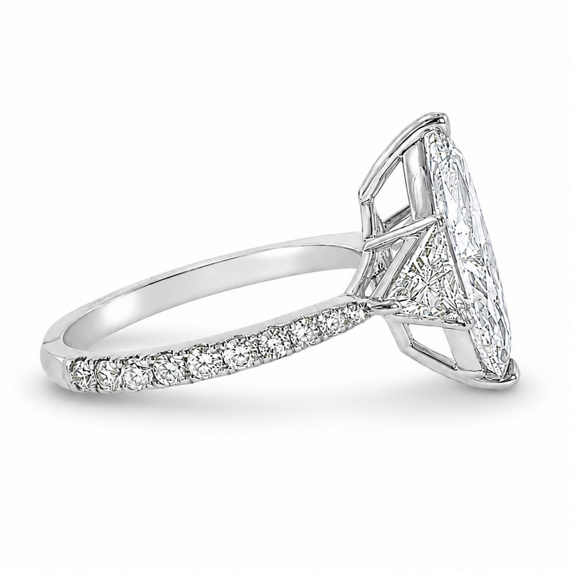 Marquise-cut lab-grown diamond three-stone engagement ring with trillion side stones and pavé diamond band.