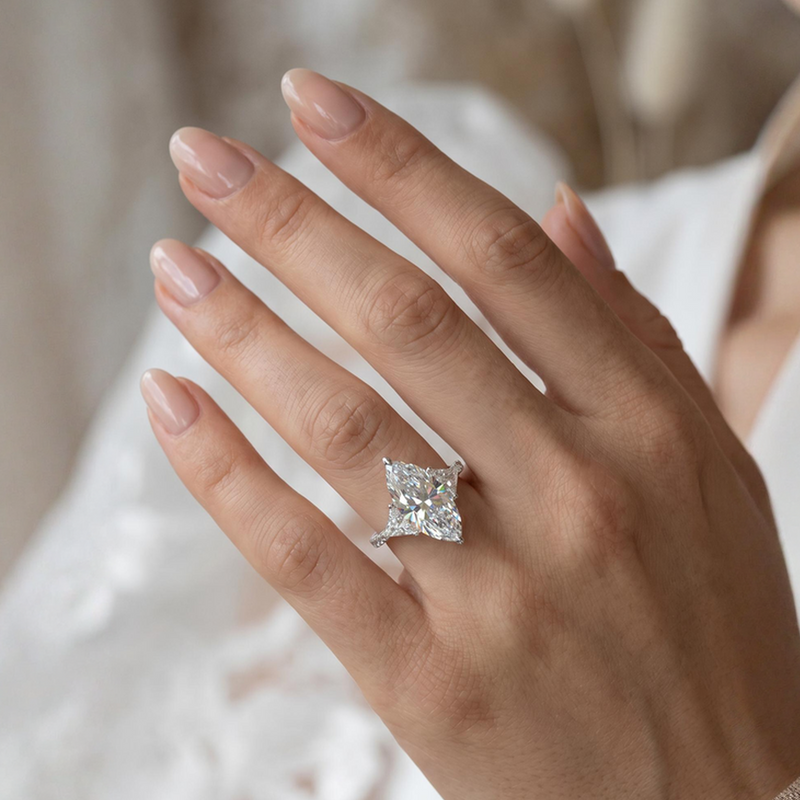 Marquise-cut lab-grown diamond three-stone engagement ring with trillion side stones and pavé diamond band.