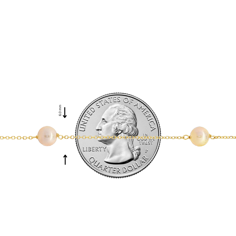 Delicate gold chain necklace with evenly spaced small white pearls, shown next to a quarter for size.