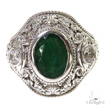 Silver men's ring with oval emerald center and intricate floral engravings.