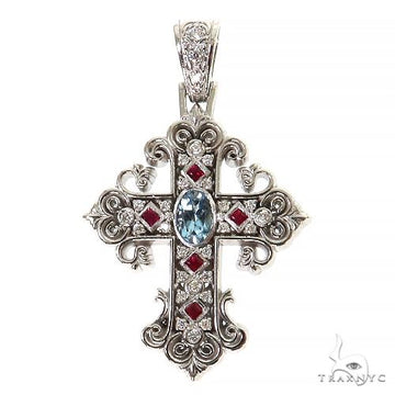 Intricate white gold cross pendant with aquamarine center, ruby accents, and diamond details.
