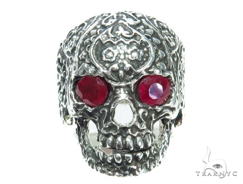 Silver skull ring with intricate floral engravings and red ruby gemstone eyes