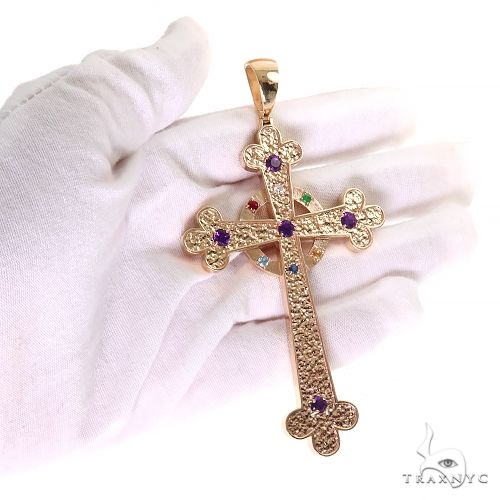 Yellow gold cross pendant with purple gemstones and intricate textured details