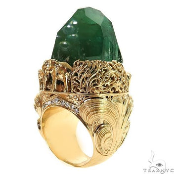 Yellow gold ring with detailed elephant and forest design and large green gemstone centerpiece.