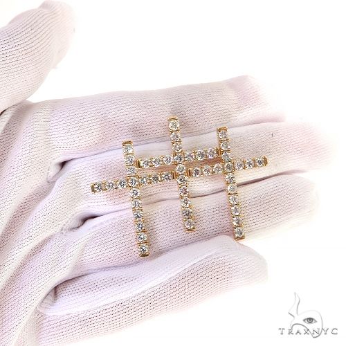 Yellow gold triple cross pendant with round diamonds on white glove background