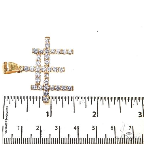 Yellow gold triple cross pendant encrusted with round diamonds, shown next to ruler for size reference