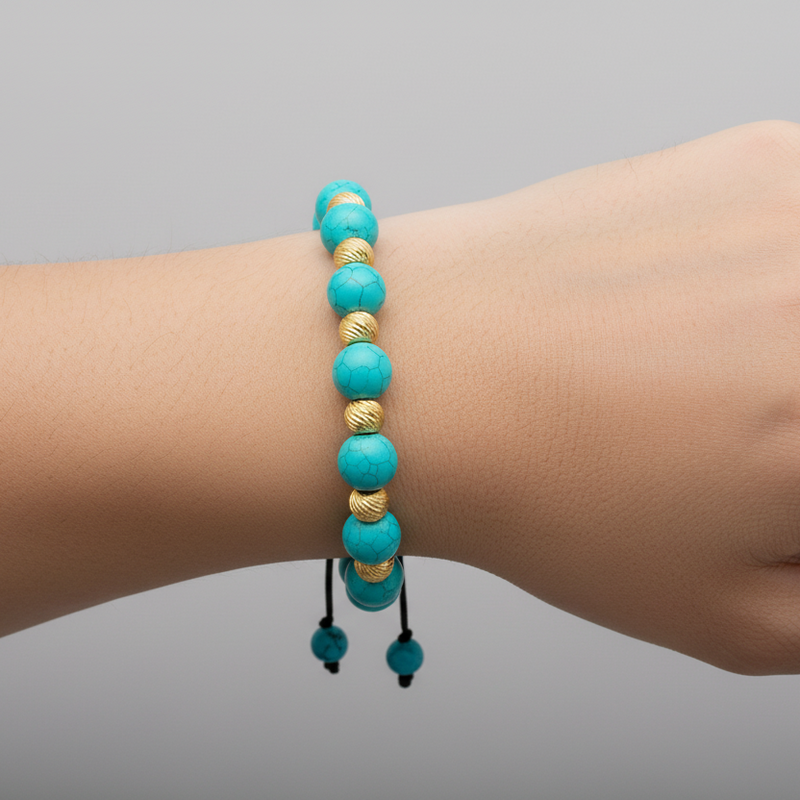 Turquoise and gold bead bracelet with adjustable black cord on wrist.