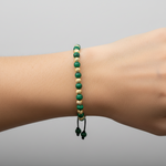 Adjustable bracelet with alternating green malachite and textured gold round beads on black cord.