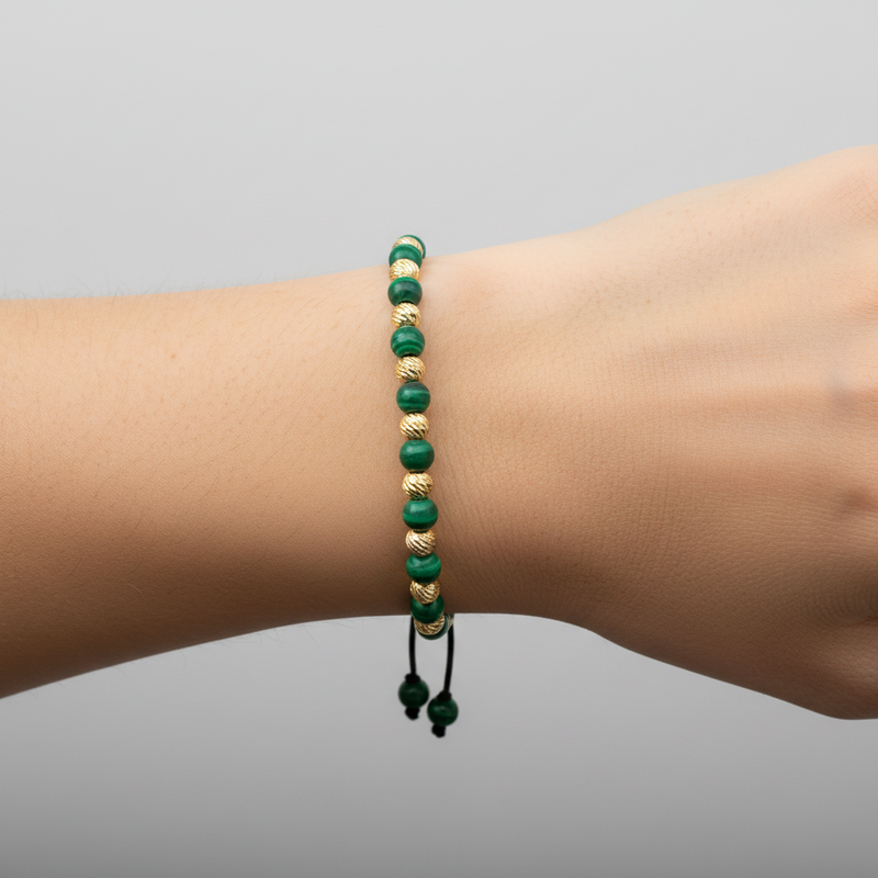 Adjustable bracelet with alternating green malachite and textured gold round beads on black cord.