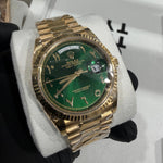Rolex Day-Date 228238 in 18K yellow gold with a green sunburst dial and gold Arabic numeral hour markers.

