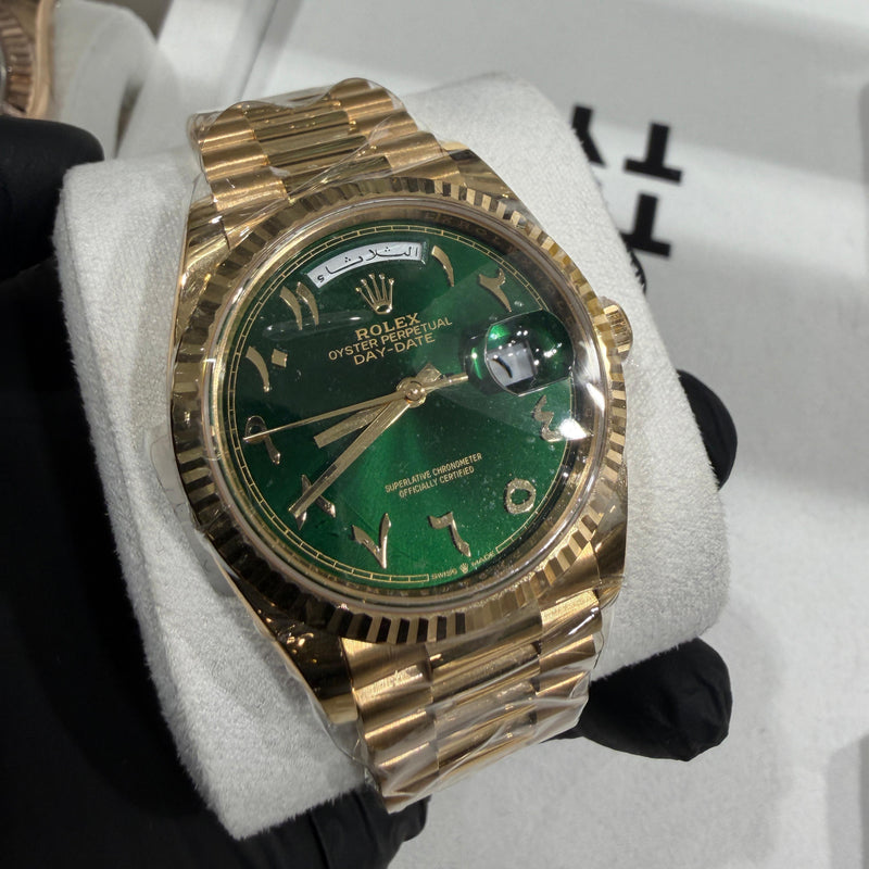 Rolex Day-Date 228238 in 18K yellow gold with a green sunburst dial and gold Arabic numeral hour markers.


