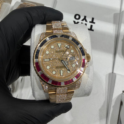 Gold luxury watch with diamond accents and red gemstone bezel on metal bracelet.