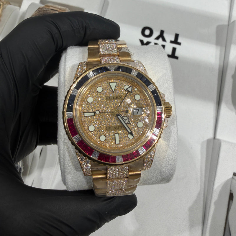 Gold luxury watch with diamond accents and red gemstone bezel on metal bracelet.
