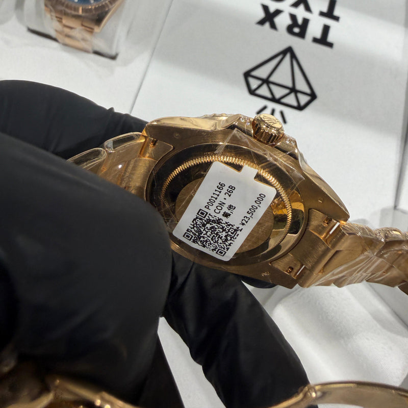 Gold-tone wristwatch with black dial and translucent protective case held by gloved hand.