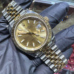 Rolex DateJust 41mm two-tone yellow gold watch with champagne stick dial and fluted bezel.