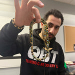 Gold chain necklace with round black opal gemstones evenly spaced around the links.