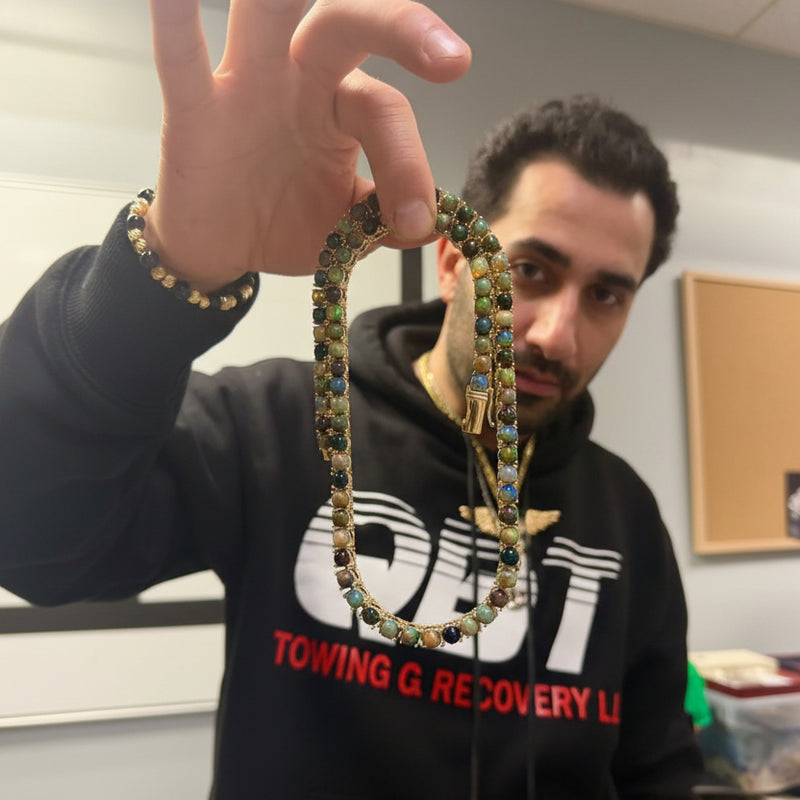 Gold chain necklace with round black opal gemstones evenly spaced around the links.