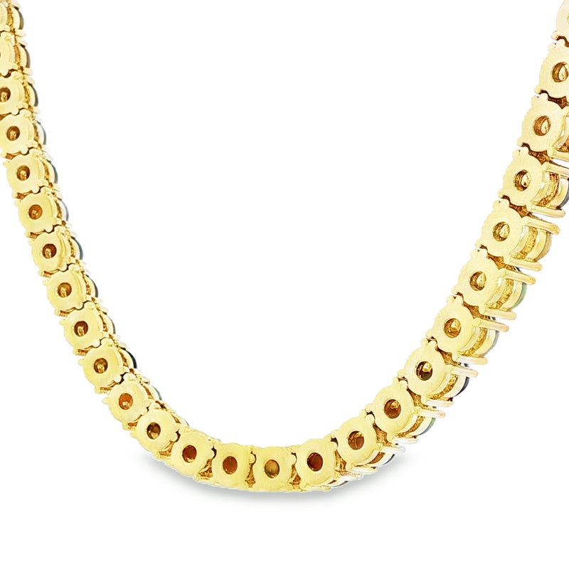 Gold chain necklace with round black opal gemstones evenly spaced around the links.