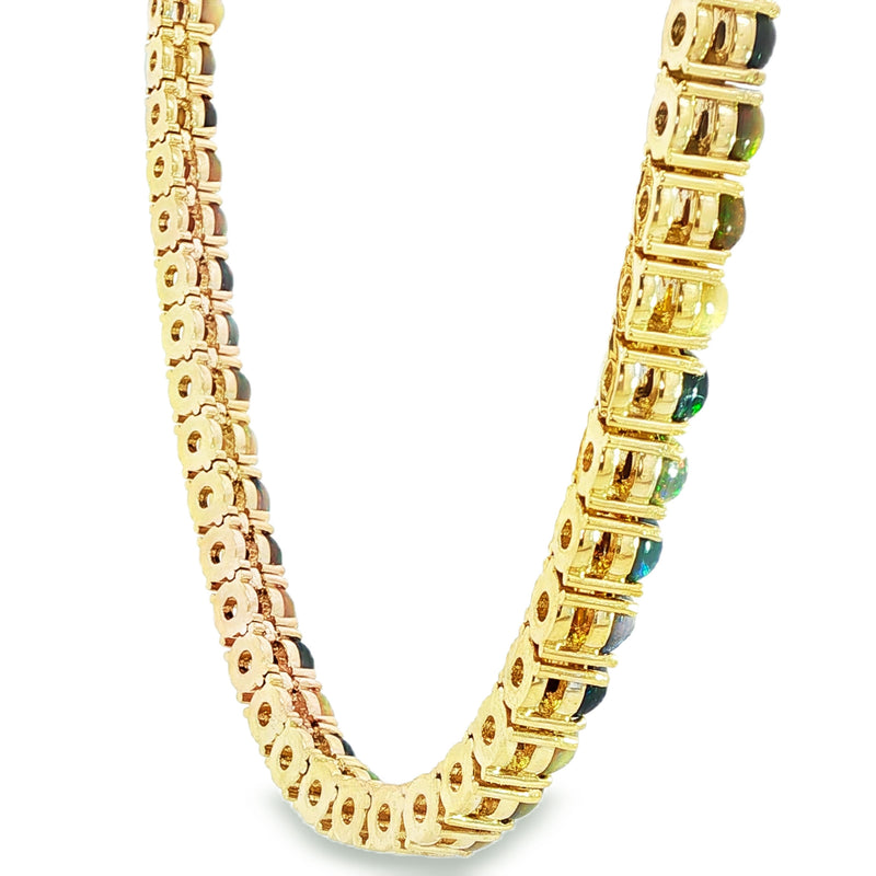 Gold chain necklace with round black opal gemstones evenly spaced around the links.