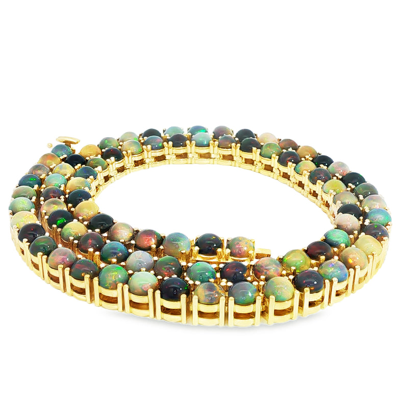 Gold chain necklace with round black opal gemstones evenly spaced around the links.