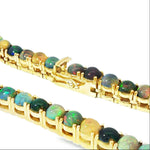 Gold chain necklace with round black opal gemstones evenly spaced around the links.