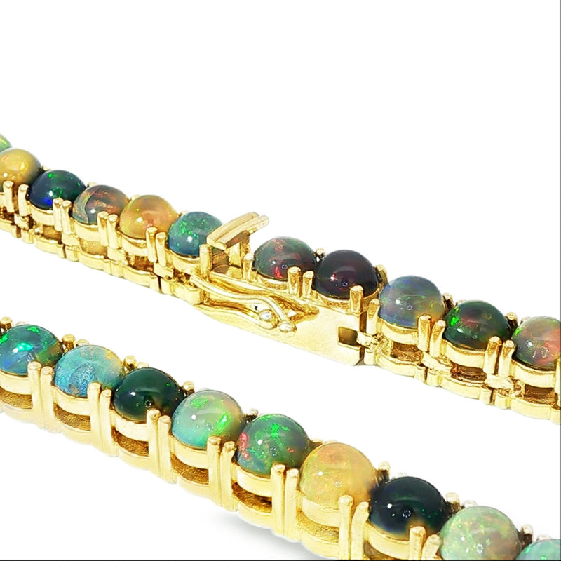 Gold chain necklace with round black opal gemstones evenly spaced around the links.