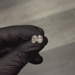 Pair of oval diamond stud earrings with cluster setting in white gold prong mount