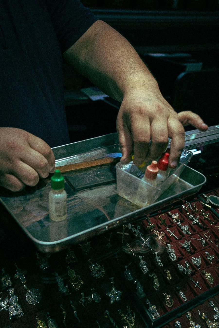 Umid's hands testing gold with the acid kit and touchstone